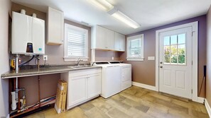 Eine Küche mit weißen Schränken, einem Einbauofen, einem Geschirrspüler und einem Fenster mit Jalousien.