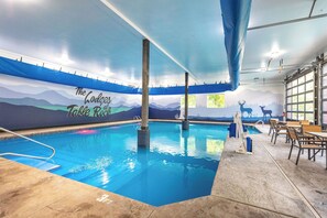 An indoor swimming pool with a mural of mountains and a deer's silhouette.