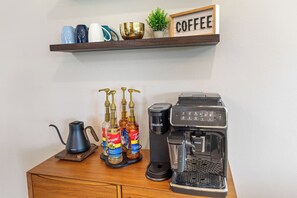 A coffee station with a Keurig machine, a French Vanilla syrup bottle, and a Terani syrup bottle. - Mid-Century Modern Retreat with Hot Tub (Branson)