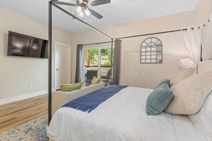 Una camera da letto con un letto, una ventola a soffitto, una finestra vista esterna e una televisione a parete.