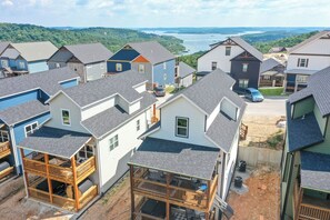 Un quartier résidentiel composé de plusieurs maisons, dont certaines sont dotées de balcons, et qui offre une vue sur une étendue d’eau au loin.