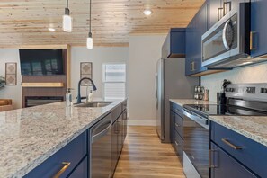 A modern kitchen with granite countertops, stainless steel appliances, and wooden ceiling. - Mid-Century Modern Retreat with Hot Tub (Branson)