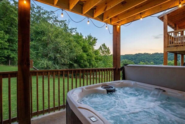 Ein Whirlpool auf einer Holzterrasse mit Blick auf ein bewaldetes Gebiet.