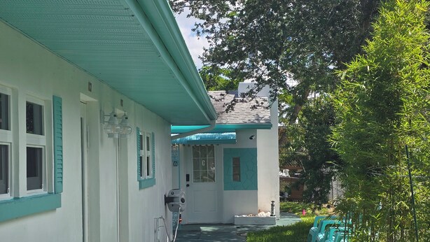 A building with a covered walkway, a door with a window, and a small garden area with chairs. - BC-8-person 4-bedroom 2 bath/Triplex in Downton Naples close to the Beach 5th Av (Naples)