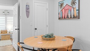 A dining area with a round table, wicker chairs, and a wall-mounted painting. - BC-8-person 4-bedroom 2 bath/Triplex in Downton Naples close to the Beach 5th Av (Naples)