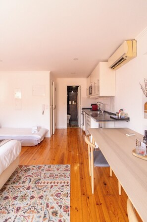 A compact room with a bed, a dining table, a kitchen area, and a hallway. - Bairro Alto Studio 3 · Very Central · AC (Lisboa)