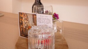 Een houten tafel met een glazen decanteerkaraf, een glazen fles, een kaart met tekst en een vaas met bloemen.
