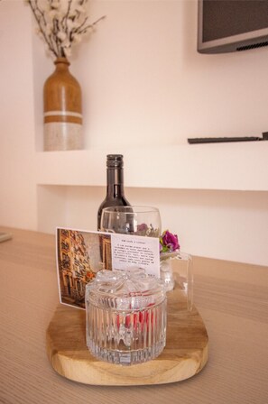 A wooden table with a glass decanter, a glass bottle, a card with text, and a vase with flowers. - Bairro Alto Studio 3 · Very Central · AC (Lisboa)