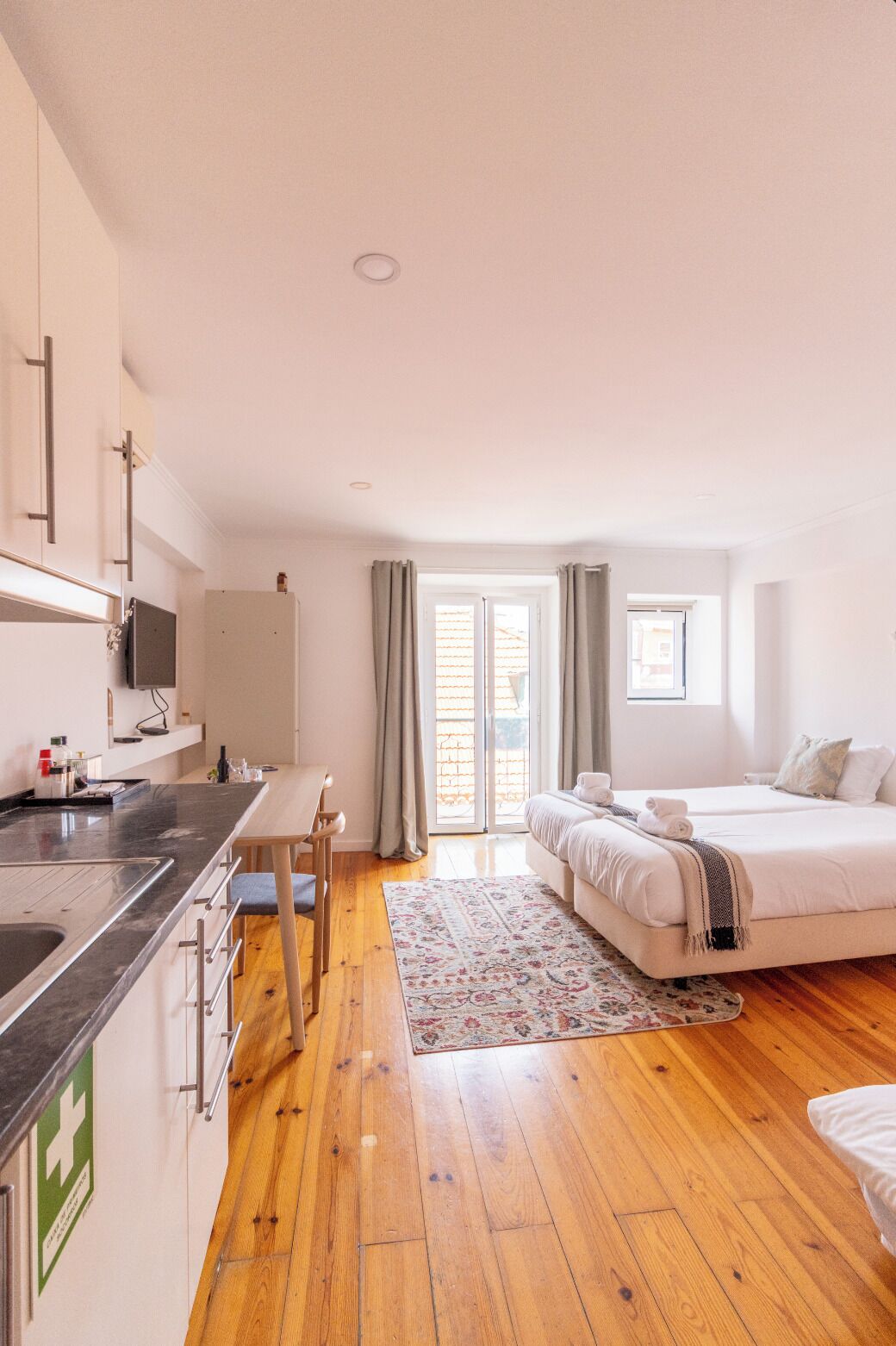 Une chambre d’hôtel moderne dotée d’une cuisine, d’un coin repas et d’un grand lit.