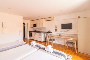 Ein Hotelzimmer mit Bett, Schreibtisch, Stuhl, Küchenzeile und Fernseher.