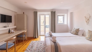 Een hotelkamer met een bed, een bureau, een televisietoestel en een raam.