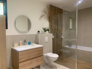 Ein modernes Badezimmer mit einem Holzkosmetikschrank, einem runden Spiegel, einer Toilette und einer Duschkabine.