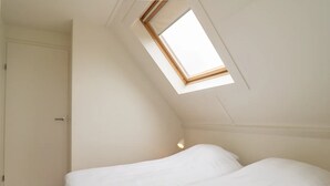 A bedroom with a skylight, a bed, and a door. - 3-bed Villa With Whirlpool (De Koog)
