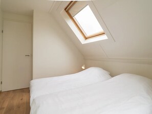 Ein Schlafzimmer mit Dachfenster, einem Bett und einer Tür.