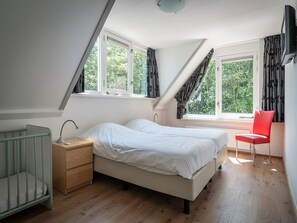 Ein Schlafzimmer mit einem Bett, einem Schreibtisch, einem Stuhl und einem Babybett.