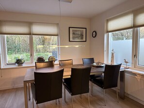 Ein Essbereich mit Tisch, Stühlen, einer Uhr und einem Fenster mit Jalousien.