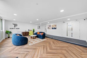 A modern interior with a herringbone wooden floor, a blue bean bag chair, a green armchair, and a white coffee table. - Stunning Spacious 2-bedroom apartment near London (Gravesend)