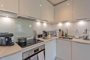 Eine moderne Küche mit Einbauherd, Kaffeemaschine und Spüle.
