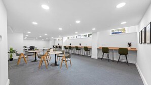 A modern office space with round tables and chairs, a long counter, and recessed ceiling lights. - Stunning Spacious 2-bedroom apartment near London (Gravesend)