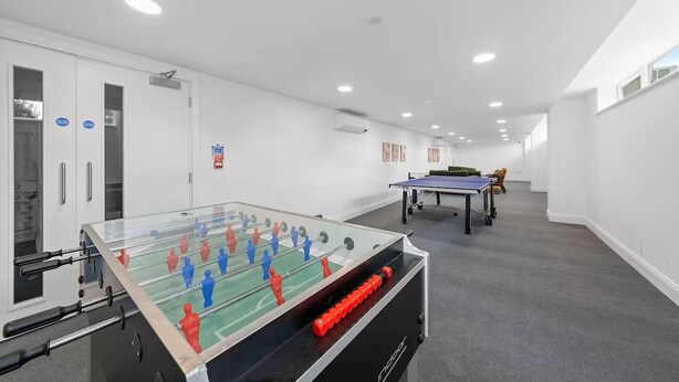 A room with a foosball table, a ping pong table, and a sofa. - Stunning Spacious 2-bedroom apartment near London (Gravesend)