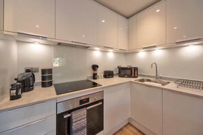 A modern kitchen with a built-in stove, microwave, and sink. - Stunning Spacious 2-bedroom apartment near London (Gravesend)