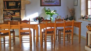 A dining area with a wooden table and chairs, a bookshelf, and a painting on the wall. - Kamares Private Pool Stone Villa (Apokoronas)