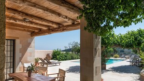 An outdoor patio area with a wooden table and chairs, a pool, and a view of the surrounding landscape. - Kamares Private Pool Stone Villa (Apokoronas)