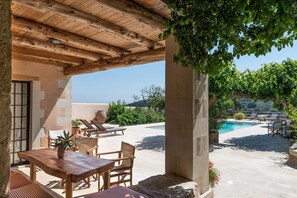 An outdoor patio area with a wooden table and chairs, a pool, and a view of the surrounding landscape. - Kamares Private Pool Stone Villa (Apokoronas)