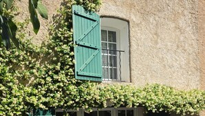 Ein rustikales Gebäude mit einer grünen Tür, weißen Fenstern und einem Balkon mit einem grünen Stuhl.
