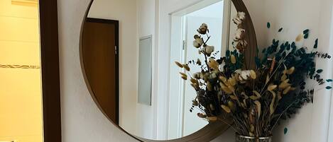 Um espelho, um vaso com flores secas e um armário branco.