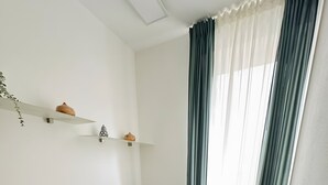 Una sala de estar moderna con un sofá, dos sillones, una mesita y una ventana con cortinas.