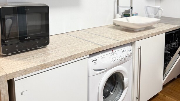 Una cocina compacta con microondas, lavamanos y lavadora.