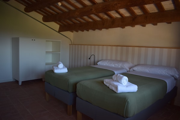 A bedroom with two beds, a wardrobe, and a sloped ceiling.