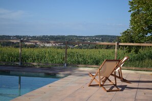 A pool area with a view of a vineyard and distant buildings. - 16th-century Catalan farmhouse with a pool, surrounded by nature, 30 meters from Barcelona (L'Ametlla del valles)