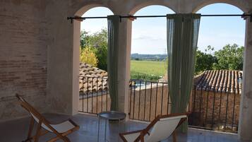 Un balcón con dos sillas de madera y una mesa pequeña, con vistas a una piscina y un jardín.