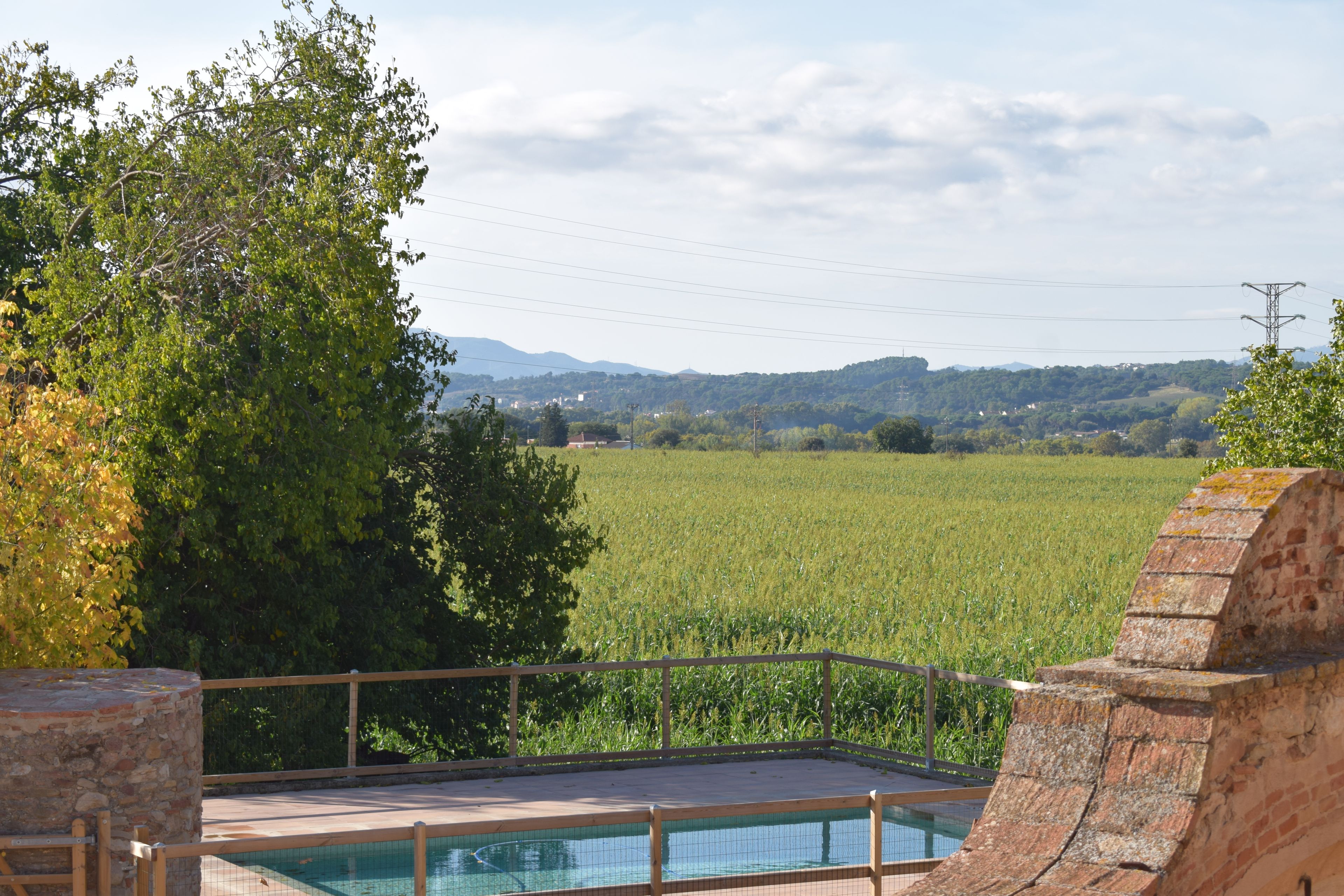 Una piscina con vistas a un campo y montañas al fondo.