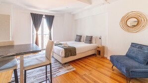 Ein modernes Zimmer mit einem Bett, einem Schreibtisch, einem Sessel und einem blauen Sofa.
