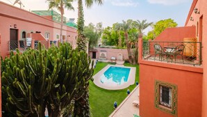 Ein Innenhof mit Swimmingpool, Palmen und einem Gebäude mit Satellitenschüssel.