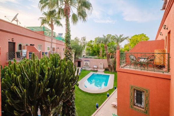 Ein Innenhof mit Swimmingpool, Palmen und einem Gebäude mit Satellitenschüssel.