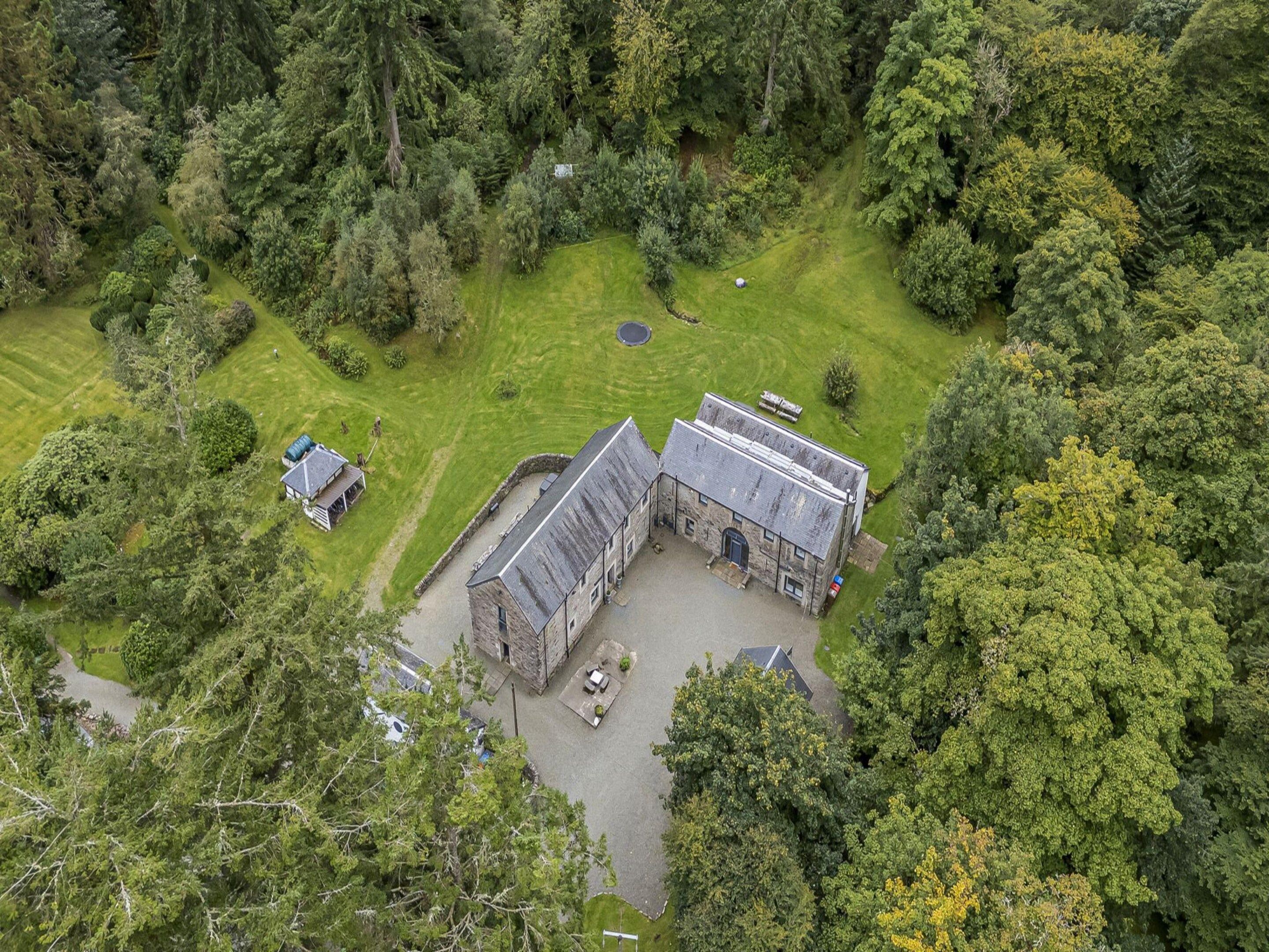 A large stone building with a courtyard, surrounded by dense forest.
