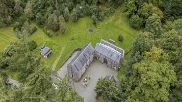 A large stone building with a courtyard, surrounded by dense forest.