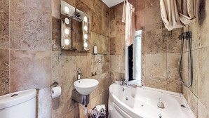A bathroom with a large bathtub, a sink, a mirror with lights, and a shower. - 9-bedroom Scottish Retreat (Colintraive)