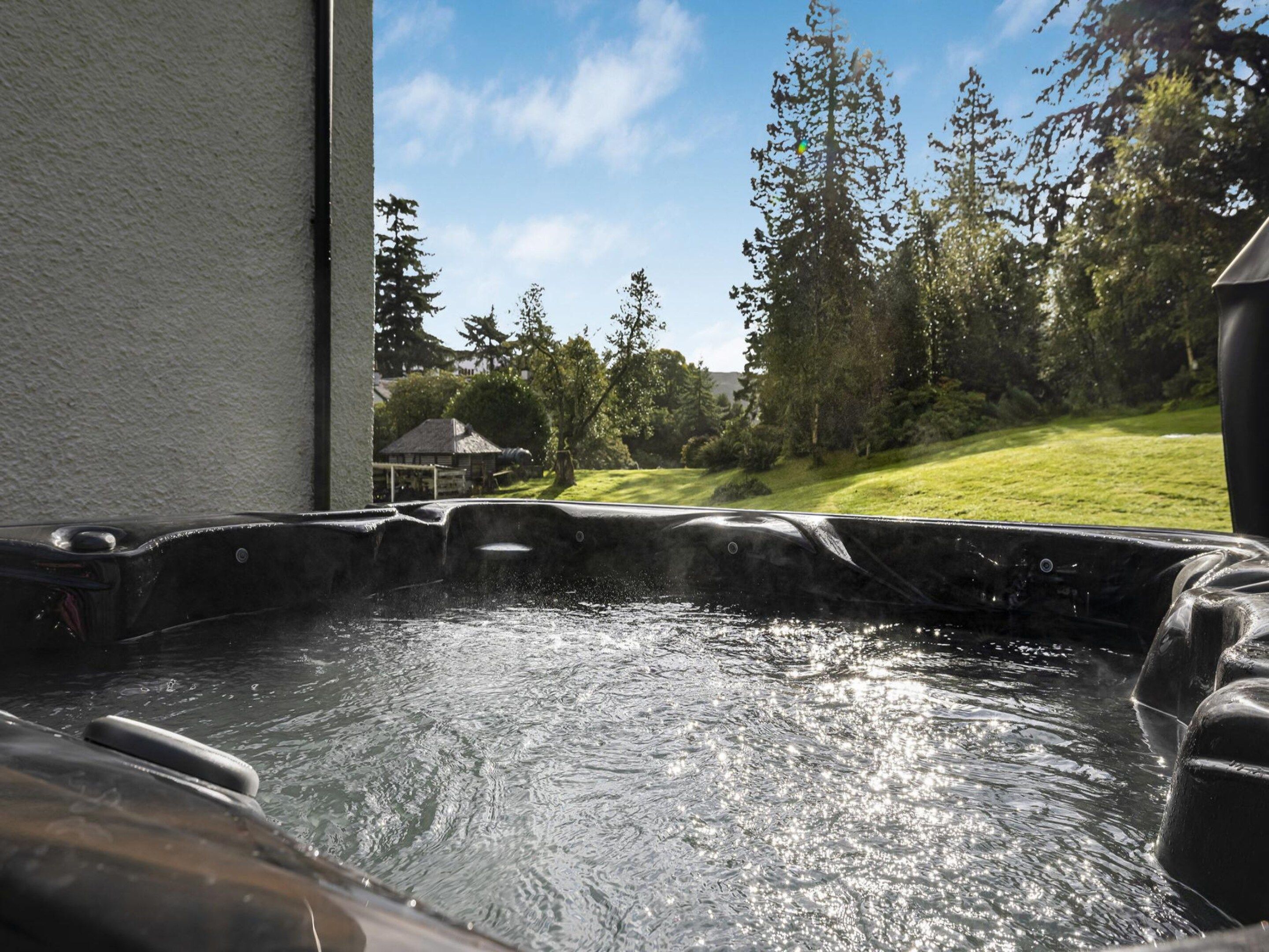 A hot tub with a view of a grassy yard and trees.