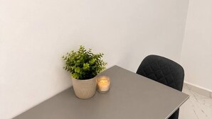 A minimalist dining table with two chairs, a potted plant, and a candle. - Cozy Bedroom Studio with Modern Kitchen & Bath (București)