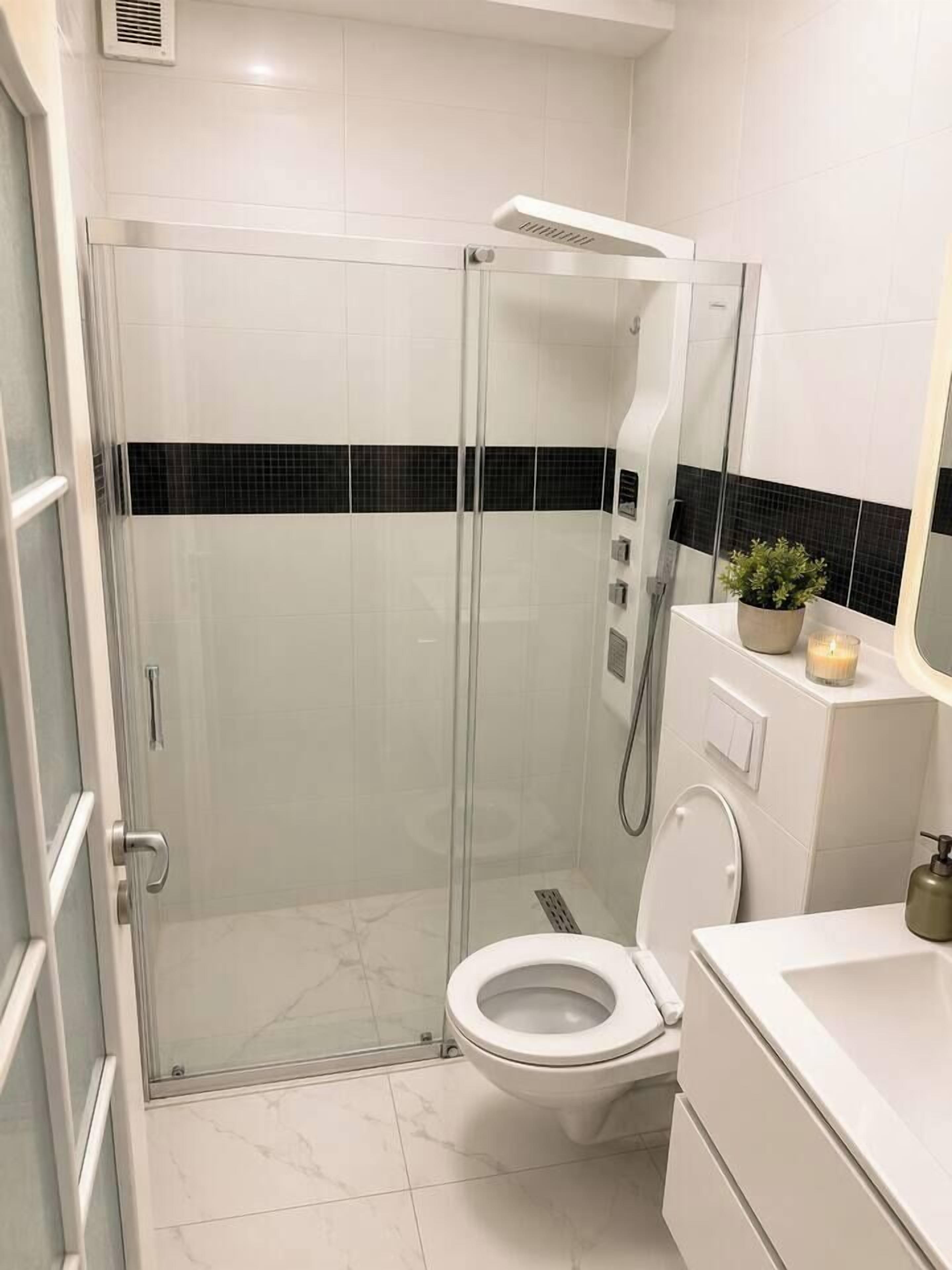 Une salle de bain moderne avec une douche à parois de verre, des toilettes et un meuble-lavabo avec un miroir.