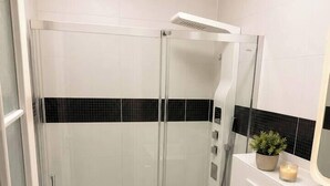A modern bathroom with a glass-enclosed shower, a toilet, and a vanity with a mirror. - Cozy Bedroom Studio with Modern Kitchen & Bath (București)