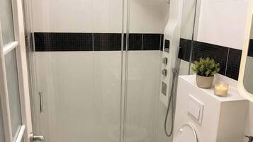 Une salle de bain moderne avec une douche à parois de verre, des toilettes et un meuble-lavabo avec un miroir.