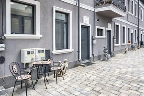 A building with a grey facade, multiple windows, and a paved courtyard with outdoor seating. - Charming Studio in a Historic Bucharest Courtyard (București)