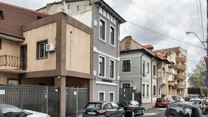 A street view with multi-story residential buildings, parked cars, and a clear sky. - Charming Studio in a Historic Bucharest Courtyard (București)