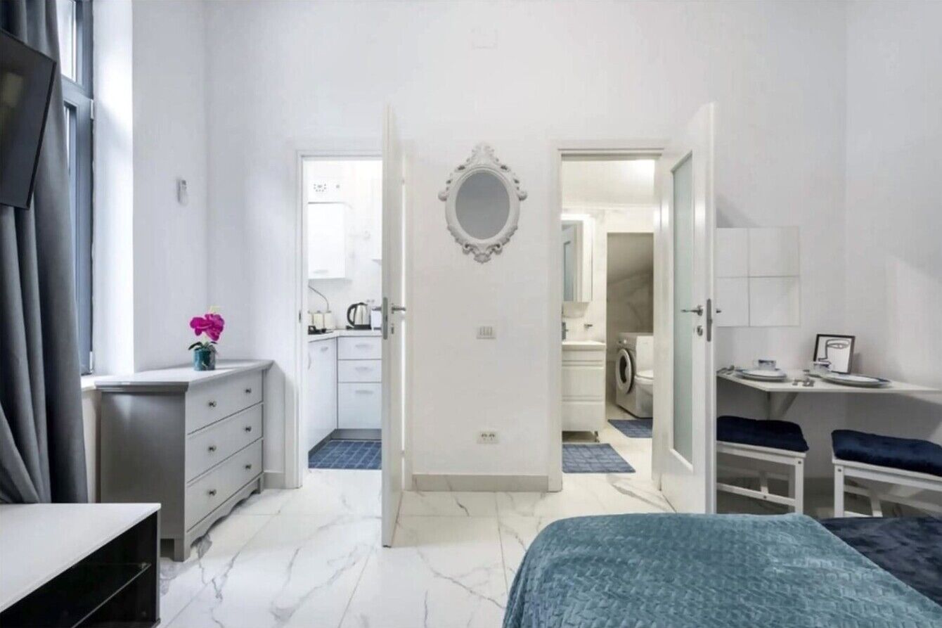 Un dormitorio con cama, cómoda, espejo y puerta que da a un baño.